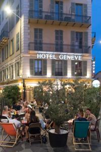 a group of people sitting at tables in front of a hotel at Hôtel Le G (ex Le Genève) in Nice