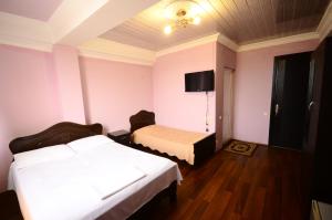 a bedroom with two beds and a tv on the wall at Hotel Peria in Batumi