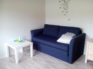 um sofá azul e uma mesa branca num quarto em Kassie & Gia's Home em Vestnanhavn