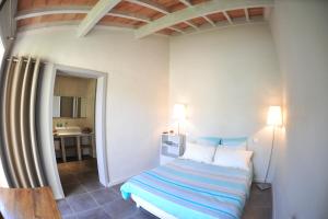 Schlafzimmer mit einem Bett mit blauer und weißer Bettwäsche in der Unterkunft L'Olivette in Montagnac