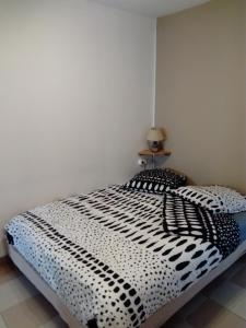 a bedroom with a bed with a black and white comforter at Studio des Grenadiers in Balaruc-les-Bains