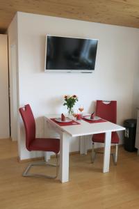 a white table with two red chairs and a tv at Ferienwohnung Haag in Uhldingen-Mühlhofen