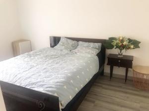 Un dormitorio con una cama y una mesa con un jarrón de flores en Cosy 74m2 apartment close to Paris, en Houilles