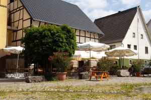 ein Gebäude mit Tischen und Sonnenschirmen davor in der Unterkunft Gasthaus zum Ochsen in Westernhausen