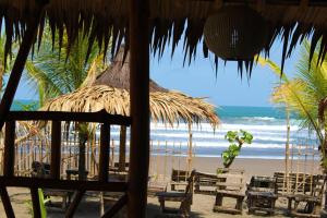 a beach with chairs and a straw umbrella and the ocean at Villadevi in Pangandaran