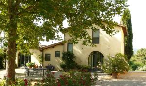Fienile villa cottage في Bucine: منزل فيه شجرة وطاولة أمامه