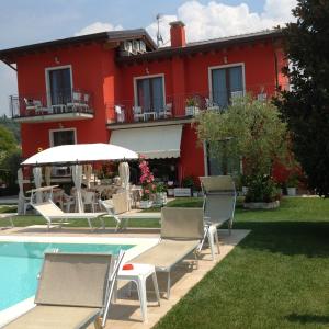 una casa roja con sillas y piscina en G&G Bed&Breakfast and apartments, en Garda