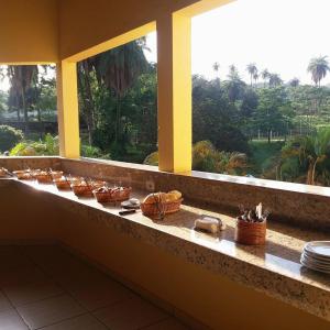 a counter with plates and baskets on a window sill at Pousada Coqueiro Verde Minas Gerais in Mateus Leme