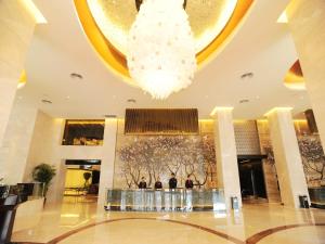 un vestíbulo con una lámpara de araña y gente de pie en él en Grand View Hotel Tianjin en Tianjin