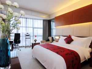 a hotel room with a large bed and a desk at Grand View Hotel Tianjin in Tianjin