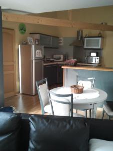 eine Küche mit einem Tisch und Stühlen sowie einem Kühlschrank in der Unterkunft charmant loft à la campagne,Hauts de France ,Somme in Rubempré