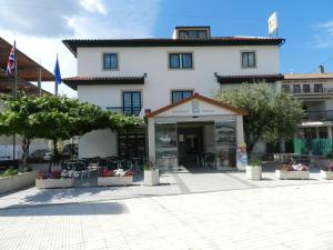 a white building with tables and chairs in a courtyard at Hotel O Encontro in Sendim