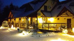 Una casa con luces de Navidad en la nieve por la noche en Neon2 - Vendégház en Orosháza
