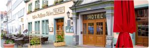 ein Gebäude in einer Stadtstraße mit einem roten Regenschirm in der Unterkunft Hotel Adler in Rudolstadt