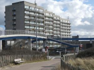 a large building with a blue bridge in front of it at Duinenzicht in Bredene