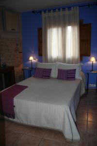ein Schlafzimmer mit einem großen Bett mit lila und weißen Kissen in der Unterkunft La Alquería in Ráfales