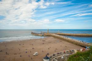 a group of people on a beach near a pier at Lobster Hall - Room Only in Whitby +10 photos