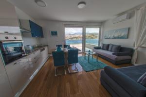 a living room with a couch and a kitchen with a television at Apartments Bouvier in Pag +27 photos