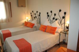 2 Betten mit orangefarbenen und weißen Kissen in einem Zimmer in der Unterkunft La Alquería in Ráfales