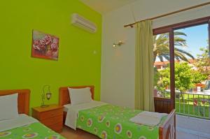 a green room with two beds and a window at Othonas Apartments in Sidari