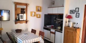 uma pequena cozinha com uma mesa e uma pequena cozinha com uma mesa e uma cozinha em La Dauphinoise Alpe d'Huez em Alpe-d'Huez