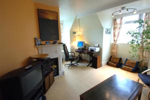 a living room with a television and a desk with a computer at Seawall, 30A Burlington Road in Swanage