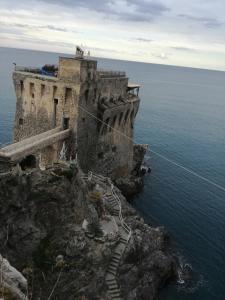 an old building on a cliff next to the ocean at La casa di Annisa in Maiori +26 photos