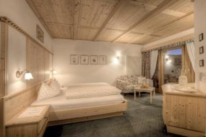 een slaapkamer met een bed en een stoel in een kamer bij Hotel Ciasa Ai Pini in San Cassiano