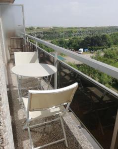 a balcony with a table and chairs and a view at Duinenzicht in Bredene