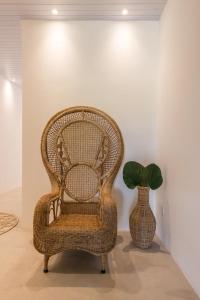 una silla de mimbre y un jarrón con una planta en una habitación en Noronha 350 en Fernando de Noronha