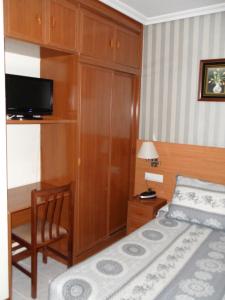 ein Schlafzimmer mit einem Bett und einem Schreibtisch mit Fernseher in der Unterkunft Hotel Alemar in Somo