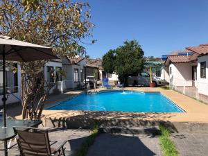 una piscina con sillas y sombrilla en Hotel Cecil en Vallenar