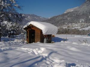 a small building covered in snow with mountains in the background at Le Gîte de la Maison Soleil, entre lac et montagne in Alex