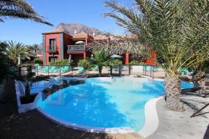 una gran piscina con palmeras frente a una casa en Apartamentos Punta Marina, en Valle Gran Rey