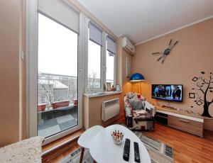 a living room with a tv and a large window at Apartman Vills in Sarajevo