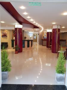 un gran vestíbulo con columnas rojas y plantas en el suelo en Mares Apart Hotel en Mar de Ajó