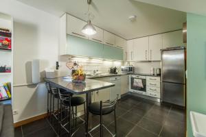 a kitchen with a counter with chairs and a refrigerator at Bairro Alegre, Casa do Porto in Porto