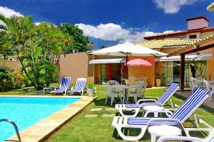 - un groupe de chaises et de tables à côté de la piscine dans l'établissement Villa Araçà - Boutique Hotel, à Lauro de Freitas