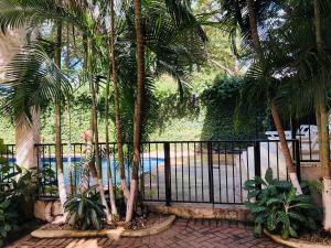 a fence with palm trees in front of a pool at La Buena Vida 2 in Tamarindo