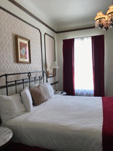 Un dormitorio con una gran cama blanca y una ventana en Mizpah Hotel, en Tonopah