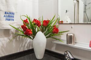 a white vase with red flowers in a bathroom at Bairro Alegre, Casa do Porto in Porto +23 photos