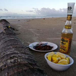 a bottle of beer and a bowl of food on the beach at Villa Encantador Resort in San Vicente