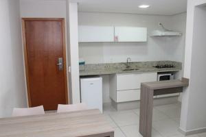 a kitchen with white cabinets and a wooden door at Atrium Thermas Residence in Caldas Novas