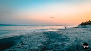 una persona in piedi sulla spiaggia al tramonto di The Corner Hostel a Playa Blanca
