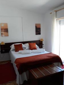 a bedroom with a large bed with orange pillows at Casa Dorita in Odeceixe
