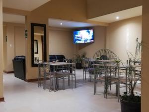 un restaurant avec des tables et des chaises ainsi qu'une télévision murale. dans l'établissement Hotel Caxa Wasi, à Cajamarca