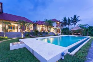 a swimming pool in front of a house at Champaca Luxury Villas Ubud in Ubud