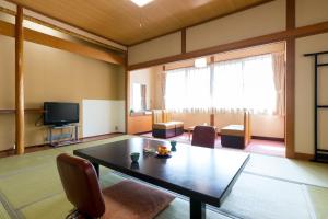 a room with a table and chairs and a television at Shosenkaku in Nagano