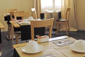 a dining room with tables and chairs with white dishes at Hôtel Ronsard in Tours