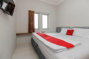 um quarto com uma grande cama branca com lençóis vermelhos em RedDoorz near Central Park Mall em Jakarta